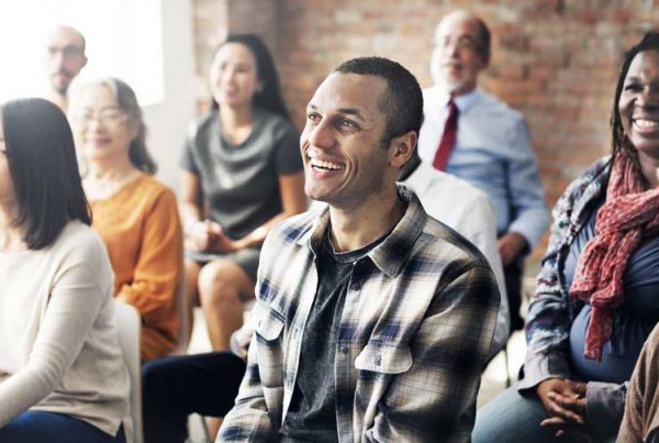 A group of people sit in a meeting, smiling