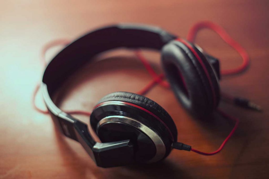 A pair of black headphones sit on a wooden table